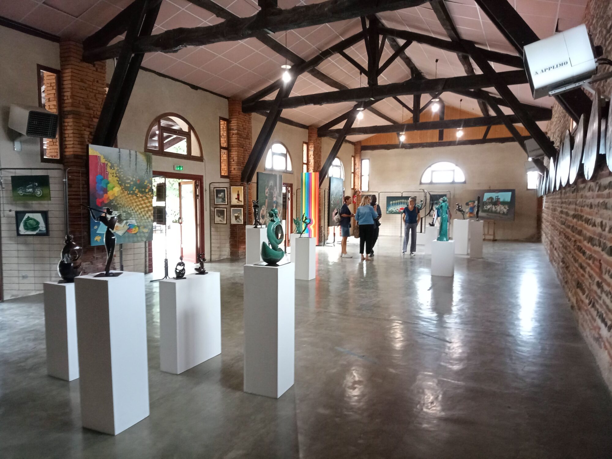 Salle d’exposition d’art avec sculptures et visiteurs en visite