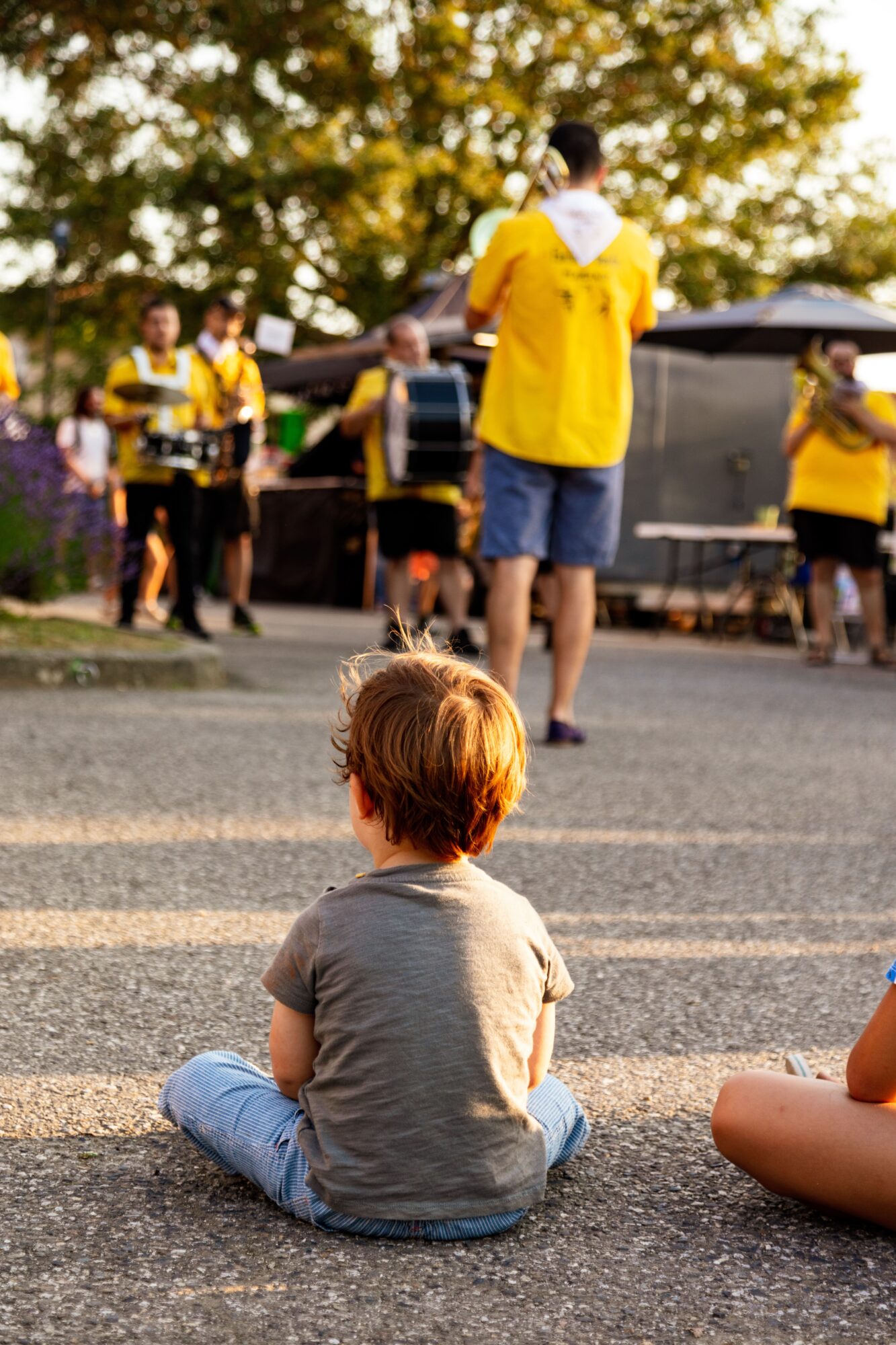 Enfant assis regardant une fanfare, Office de Tourisme Cœur de Garonne