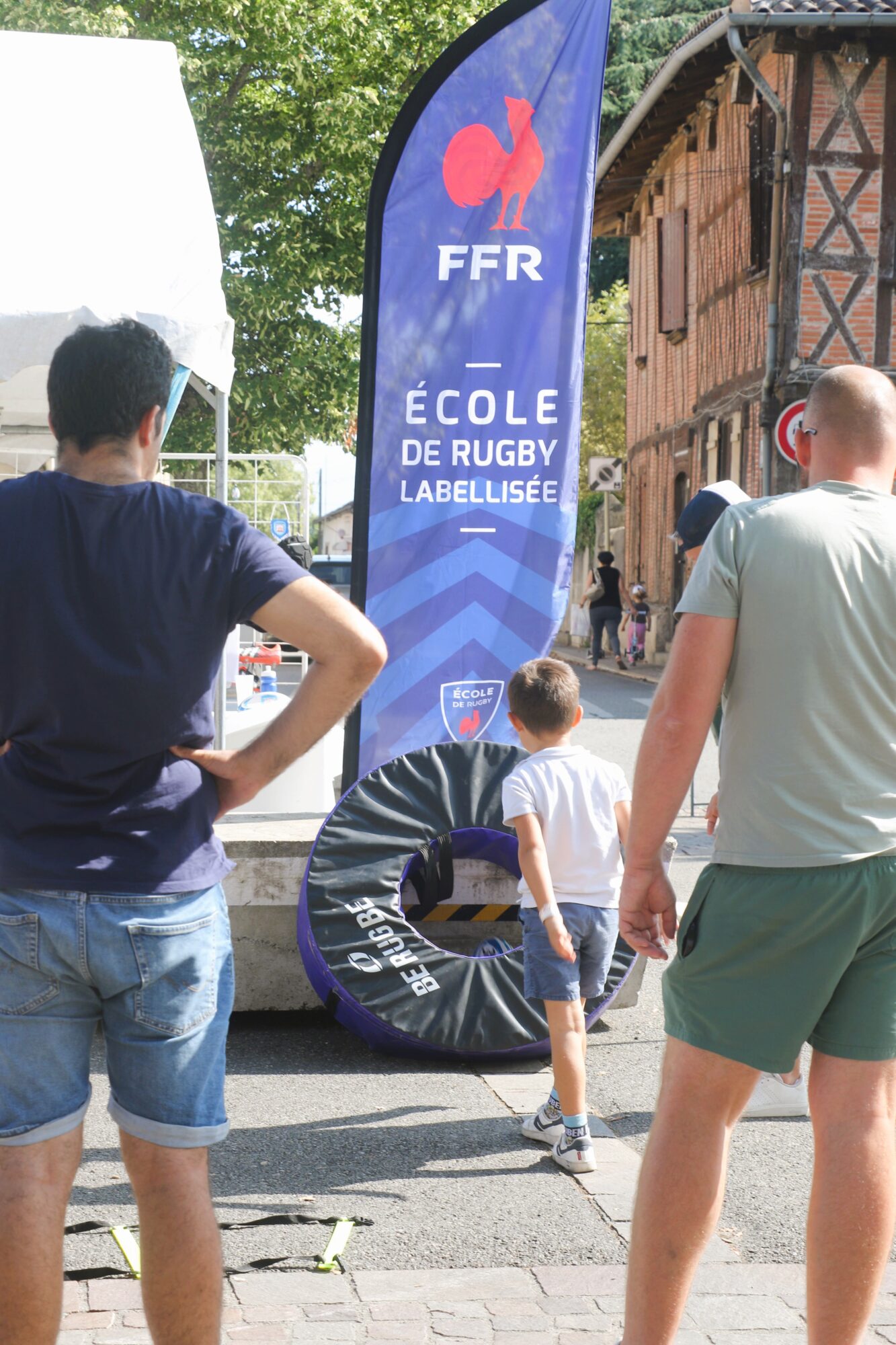 Drapeau FFR École de rugby labellisée et enfant près d’un atelier rugby
