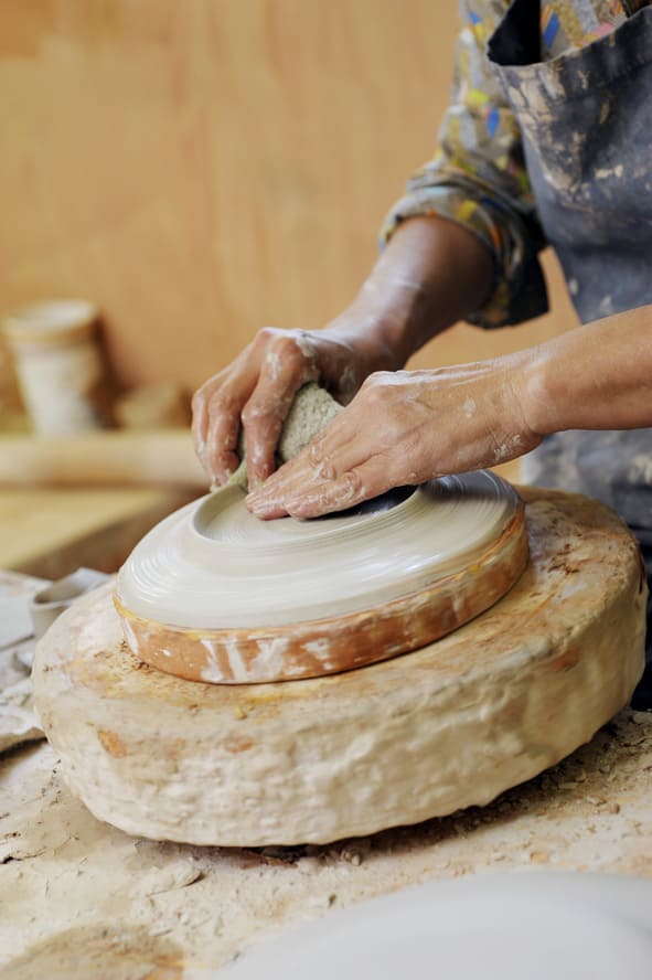 Mains de potier façonnant une pièce en argile sur un tour de poterie