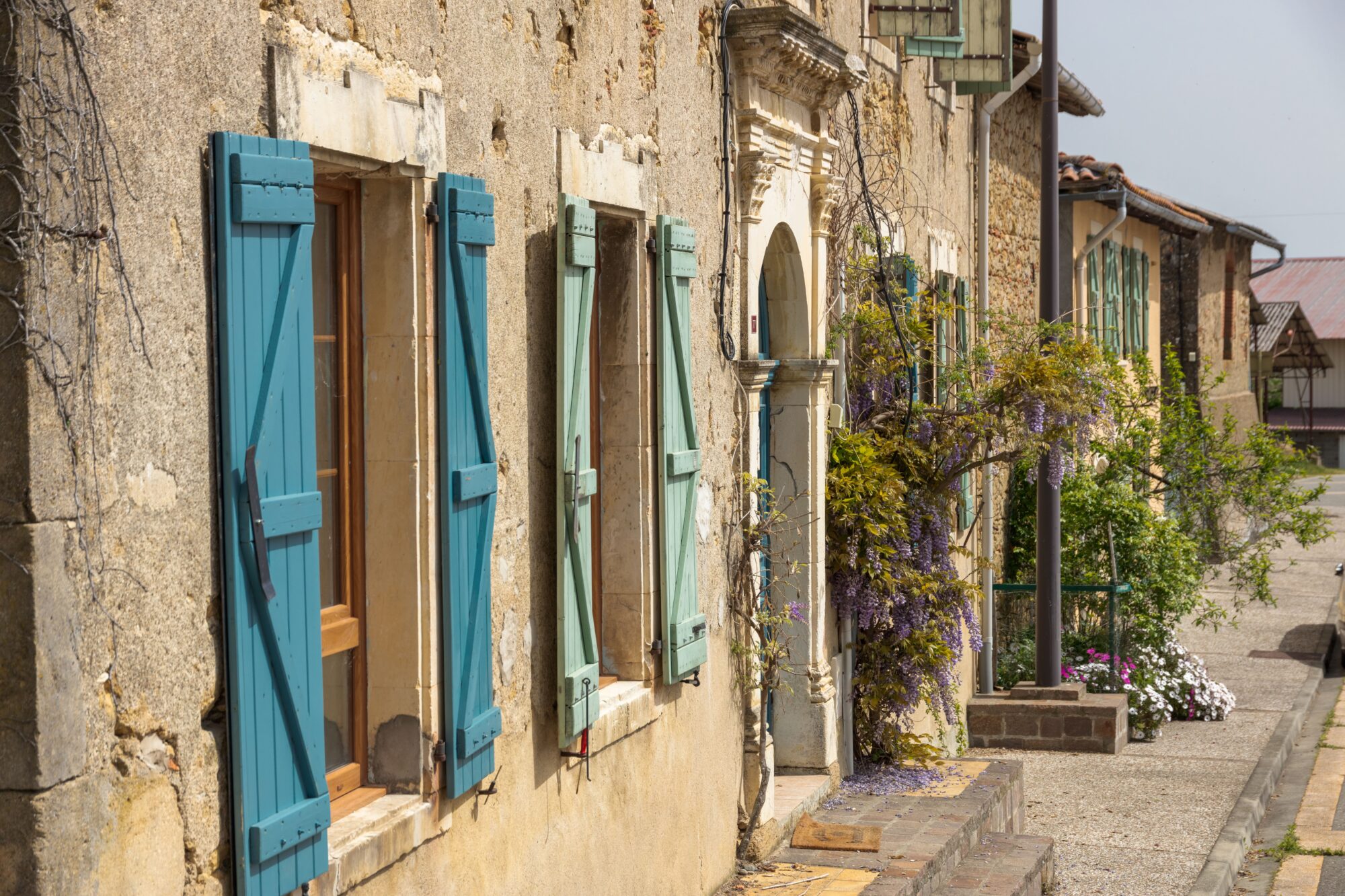 Façades en pierre aux volets bleus dans un village du Cœur de Garonne