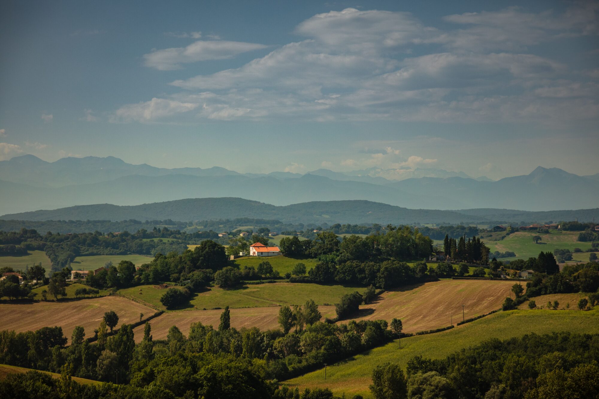 Paysage vallonné du Cœur de Garonne avec maison et montagnes
