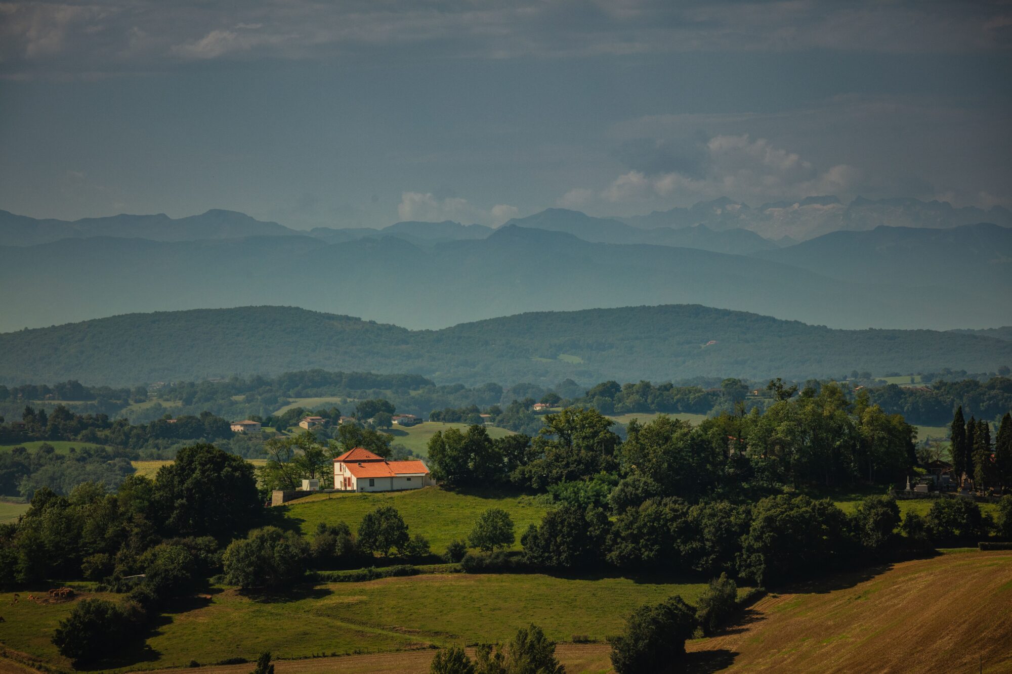Paysage vallonné du Cœur de Garonne avec maison isolée et montagnes