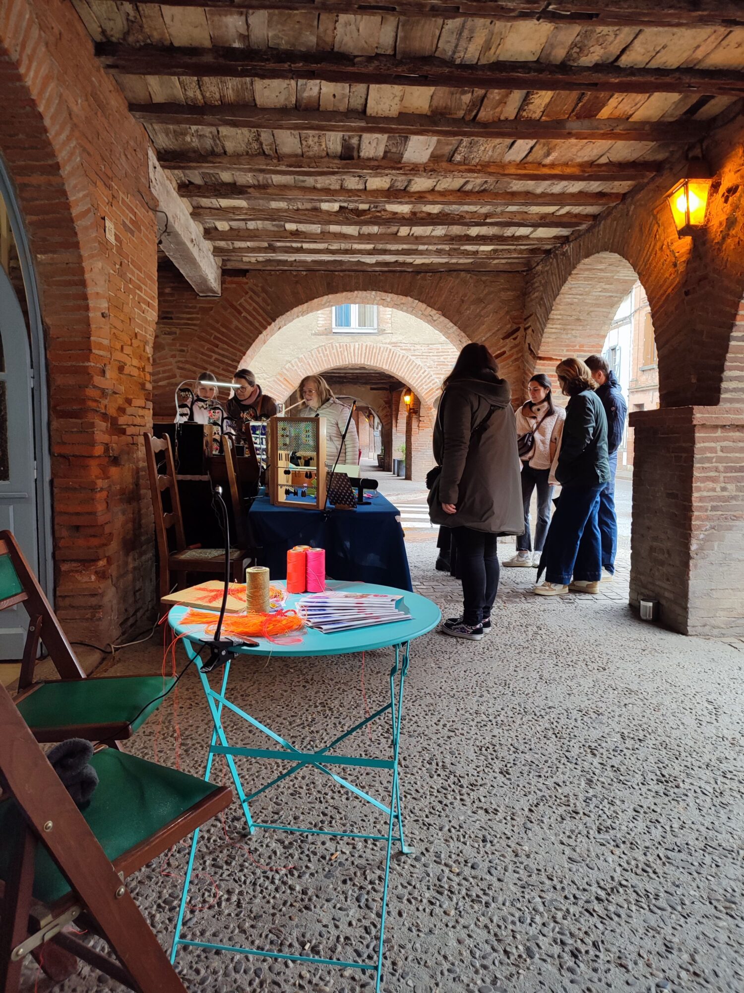 Visiteurs autour d’un stand d’artisanat sous arcade à Cœur de Garonne