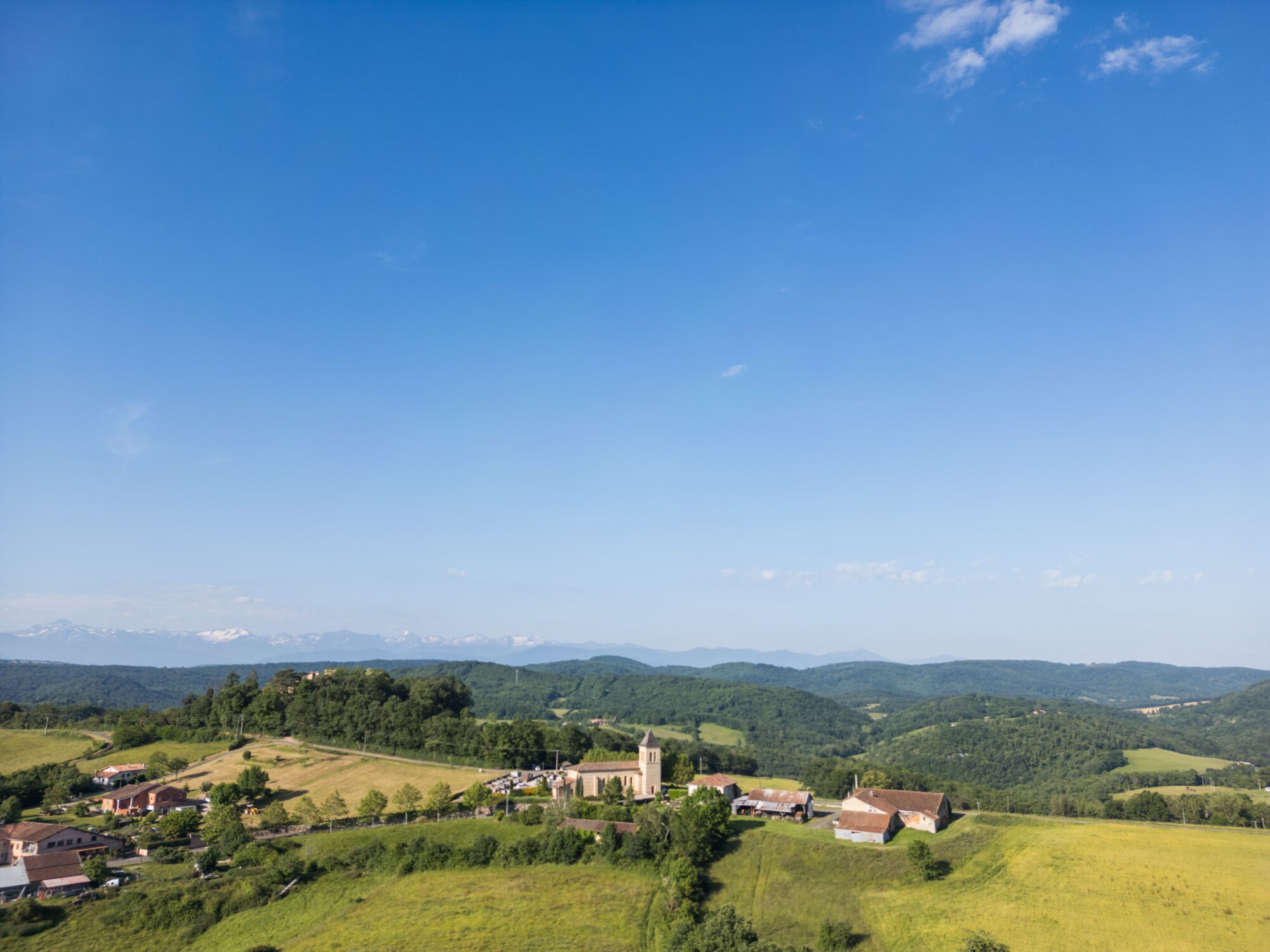 Village et église en Cœur de Garonne avec collines et montagnes au loin