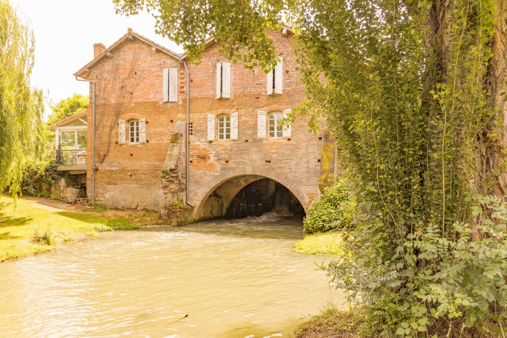 Ancien moulin en brique traversé par une rivière, Cœur de Garonne