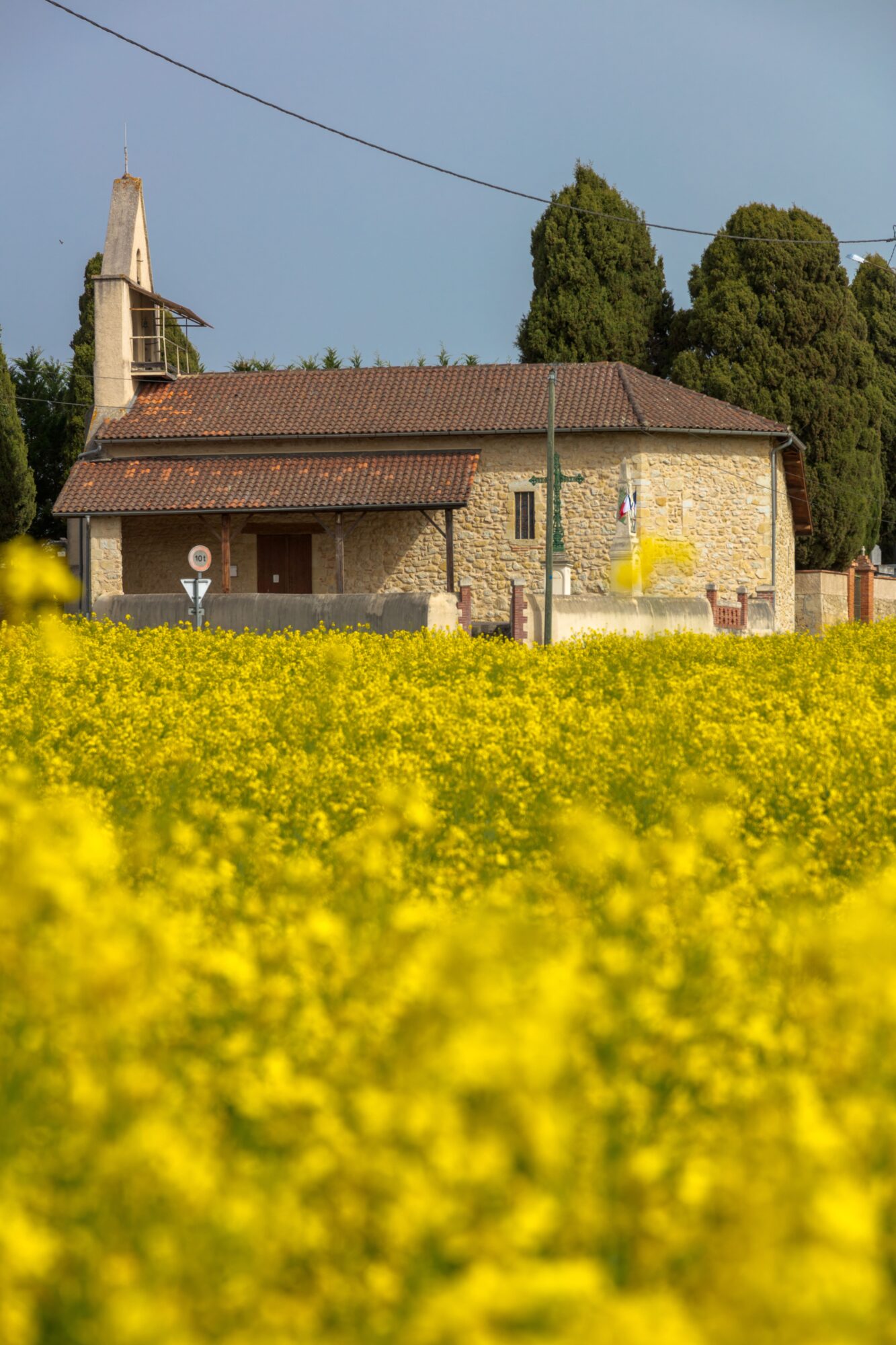 Chapelle en pierre derrière un champ de colza, Cœur de Garonne