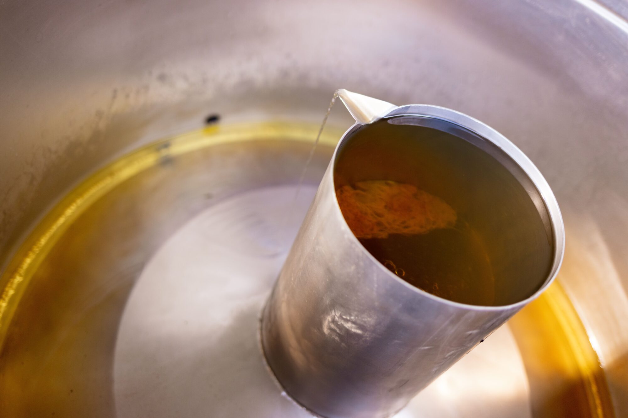 Cuve en inox avec liquide ambré en cours d’écoulement