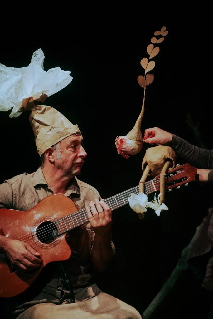 Musicien avec guitare et marionnette lors d'un spectacle vivant