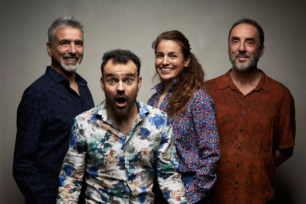 Portrait de quatre adultes souriants, dont un homme à l’expression surprise