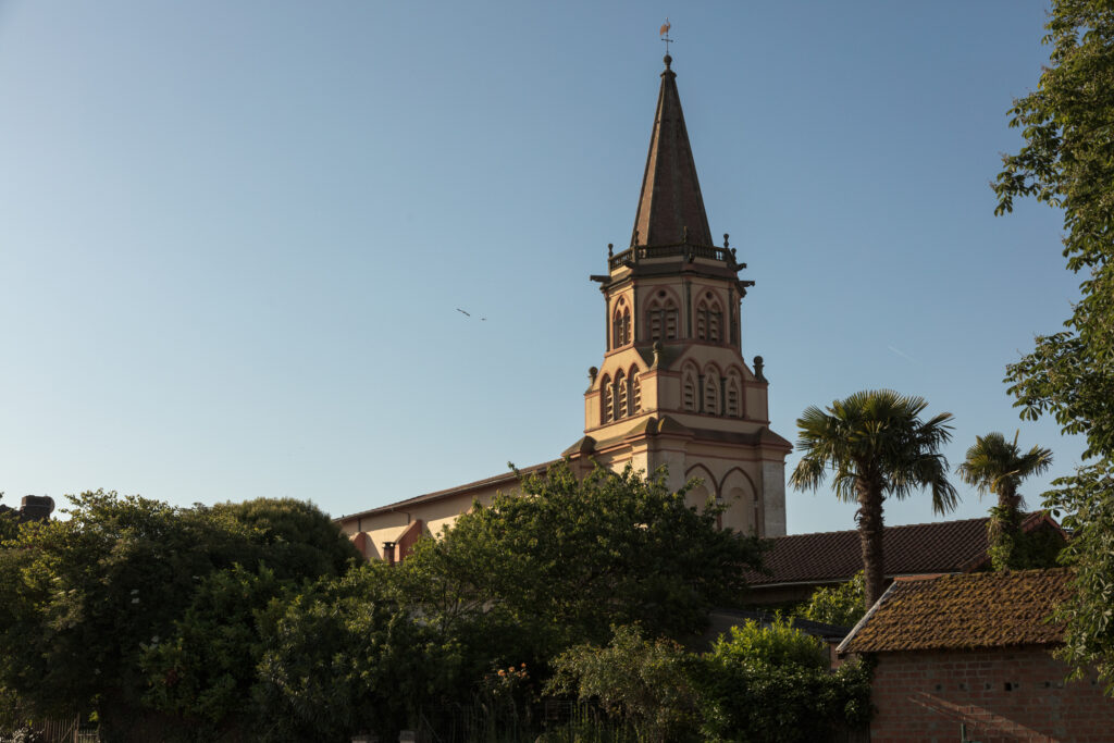 Clocher d’église du Cœur de Garonne vu au-dessus des toits et arbres