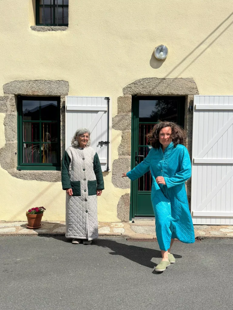 Deux femmes en robes matelassées devant une maison en pierre